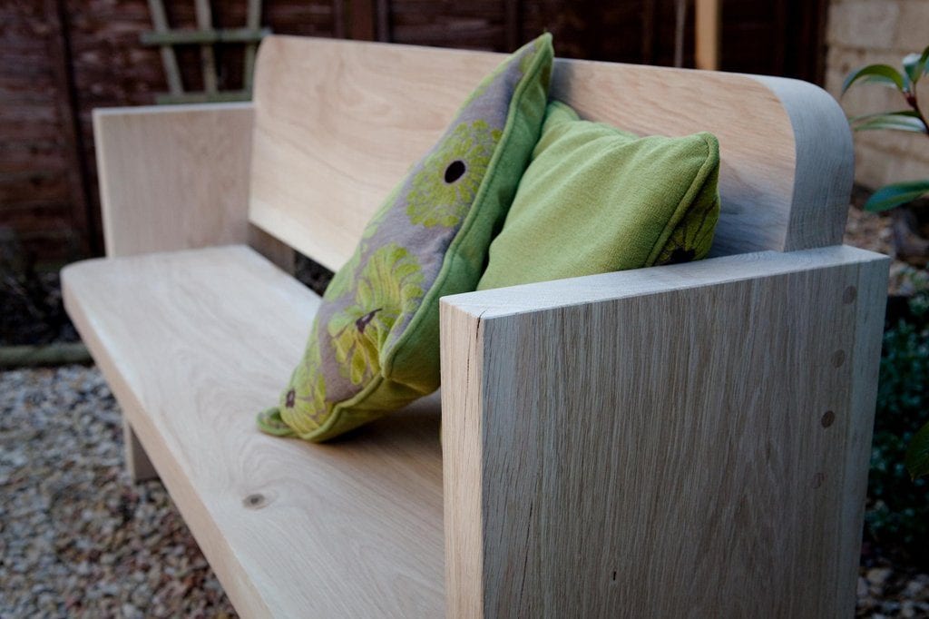 Modern handmade timber garden bench styled with green cushions